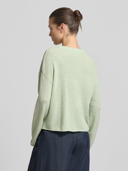 Vrouwenmodel draagt Relaxed Fit Strickpullover mit U-Boot-Ausschnitt van Tom Tailor Denim in effen lichtgroen fijngebreid materiaal, lange mouw, rolzoom aan mouw en zoom, achteraanzicht volledige lichaamsopname.