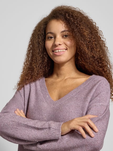 Frauenmodel trägt Regular Fit Strickpullover mit Paillettenbesatz Modell 'ARIZONA' von Only in Melange-Optik, V-Ausschnitt, Langarm, Strick, Nahaufnahme Oberkörper.