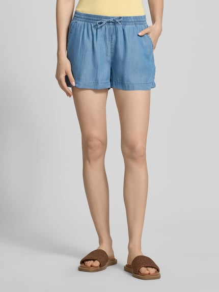 Vrouwenmodel draagt Regular Fit Jeansshorts uit lyocell model 'PEMA LIFE' van Only met denimlook, tunnelkoord, elastische boord, zij-steekzakken, materiaal lyocell, detailopname onderlichaam, vooraanzicht.
