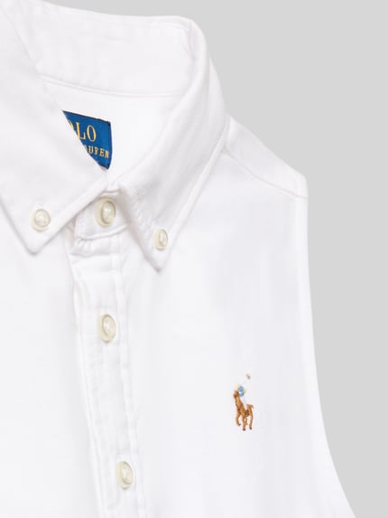 Mädchen trägt Tailliertes Hemdblusenkleid aus Baumwoll-Mix Modell 'LATOYIAOXFSD' von Polo Ralph Lauren Teens, Optik: Unifarben, Hochgeschlossen, Logo-Stitching, Knopfleiste, Ärmelform: Ohne, Mini-Länge, Ganzkörperansicht von vorne.