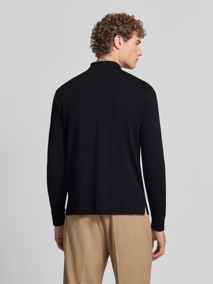 Männermodel trägt Slim Fit Poloshirt aus reiner Baumwolle von Polo Ralph Lauren in Schwarz und Beige, Ganzkörperansicht Rückansicht.