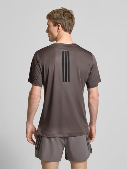 Männermodel trägt Regular fit T-shirt met Logoprint model 'Power' van adidas Training in bruin, ruglengte maat M 65 cm, Ganzkörperansicht Rückansicht