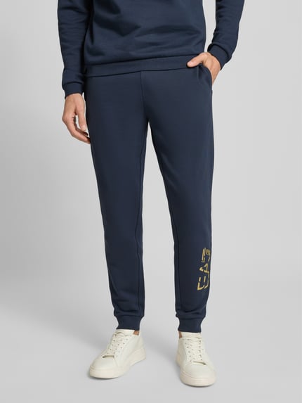 Männermodel trägt Sweatpants mit elastischem Bund und Label-Print von EA7 Armani, Reine Baumwolle, Regular-Fit, Nahaufnahme Unterkörper