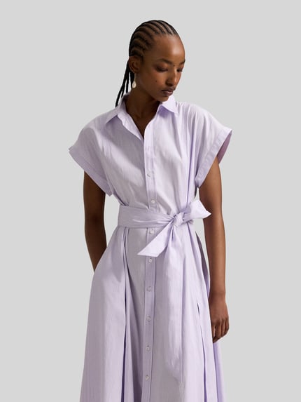 Vrouwenmodel draagt tailliertes Hemdblusenkleid aus reiner Baumwolle van Polo Ralph Lauren, look: effen, getailleerd, maxilengte, hooggesloten, applicatie: gestikt logo, sluiting: knoopsluiting, tailleriem om te strikken, mouwvorm: met korte mouwen, rechte zoom, zij-ingestoken steekzakken, materiaal: puur katoen. Nahaufnahme bovenlichaam, schuin van voren.
