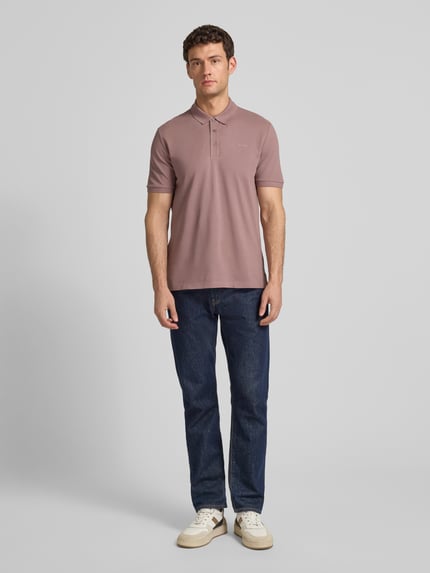 Męski model nosi Regular Fit Poloshirt aus reiner Baumwolle Modell 'DONOS222' od HUGO, piqué, jednolity kolor, krótki rękaw, widok z przodu pełnej sylwetki.