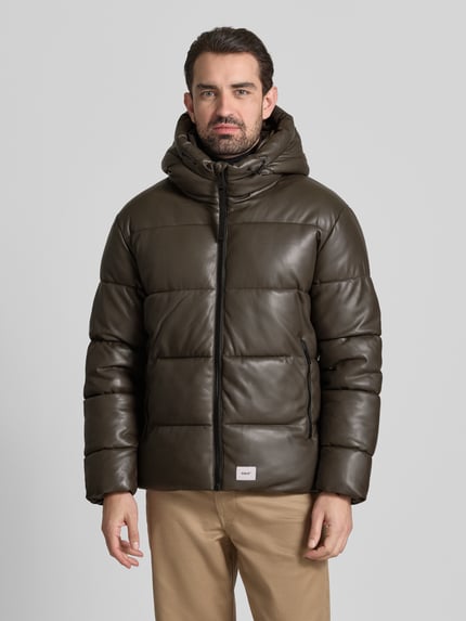 Männermodel trägt Regular Fit Steppjacke mit Logo-Patch Modell 'Coen' von khujo in dunklem Braun, sichtbarer Reißverschluss, gesteppt, Kapuze, Ganzkörperansicht von vorne