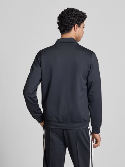 Männermodel trägt Sweatjacke mit Reißverschlusstaschen Modell 'TOSCIANA' von Ellesse, Material-Mix, schwarze Farbe, Rückenansicht.