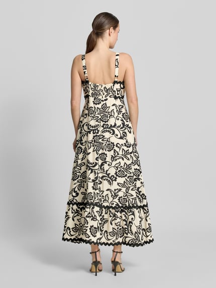 Modelka nosi Midikleid aus Viskose-Mix mit Wellensaum od Apricot, kremowy w czarny wzór, taliowany fason, prostokątny dekolt, szerokie ramiączka, marszczony detal i zapięcie na haftkę i zamek błyskawiczny z tyłu, długość tyłu w rozmiarze S: 118 cm, szerokość w rozmiarze S: 40 cm, widok całej sylwetki od tyłu.
