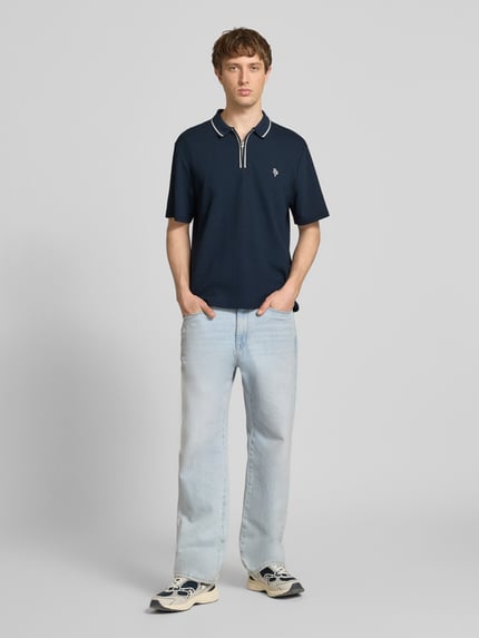 Männermodel trägt Regular Fit Poloshirt mit Reißverschluss und Label-Stitching von REVIEW, Material-Mix, Strukturmuster, Ganzkörperansicht von vorne.