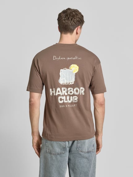 Männermodel trägt T-Shirt mit Motiv-Print und Rundhalsausschnitt von Drykorn, braun, reine Baumwolle, Regular Fit, Rückansicht Ganzkörperansicht.