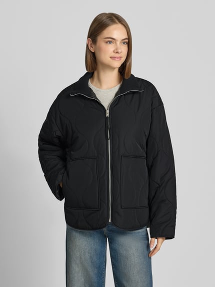 Vrouwenmodel draagt gewatteerd jack van JJXX, Model 'SERENA', doorgestikte naden, gebreide opstaande kraag, ritssluiting, steekzakken, loose fit, zwart, voorkantaanzicht, ruglengte maat S 89 cm, schouderbreedte 58 cm, borstwijdte 57 cm, mouwlengte 55 cm.