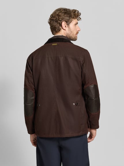 Männermodel trägt Funktionsjacke mit gewachstem Twill von Barbour in Dunkelbraun, einfarbig, Druckknöpfe, Stehkragen, langarm, Ganzkörperansicht Rückansicht.