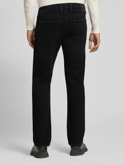 Männermodel trägt Modern Fit Jeans aus Baumwoll-Mix Modell 'Arne' von MAC in Dark Wash Denim mit 5-Pocket-Design, Ganzkörperansicht Rückansicht.