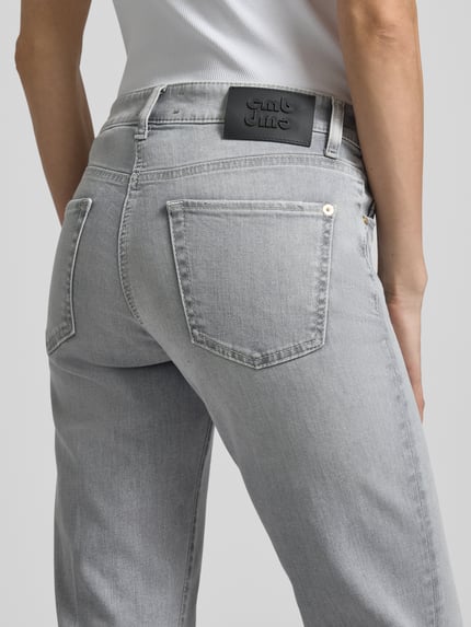Frauenmodel trägt Flared Fit Jeans aus Baumwoll-Mix von Cambio in hellgrau mit 5-Pocket-Design, Detailaufnahme Rückansicht.