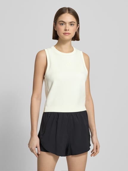 Frauenmodel trägt Tanktop mit geripptem Rundhalsausschnitt von adidas Sportswear im Material-Mix mit Modal-Anteil, lockerem Schnitt, Label-Detail in Weiß und Schwarz, Rückenlänge bei Größe S: 50 cm, Ganzkörperansicht von vorne.
