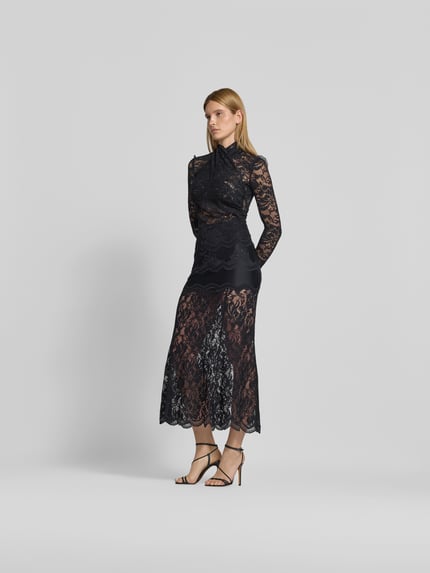 Kobiece modelka nosi Slim Fit Bluse aus Spitze od Rabanne, czarna koronka, elastyczny materiał, stójka, długie rękawy, krój slim fit, długość tyłu w rozmiarze S/M: 62 cm, widok całej sylwetki z przodu