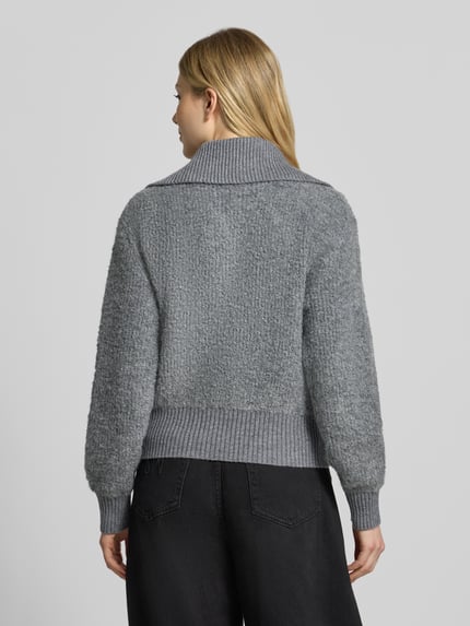 Modelka nosi Regular Fit Strickjacke mit Zweiwege-Reißverschluss Modell 'Teski' od someday., szary melanż, gruba tekstura, widok całej sylwetki z tyłu, długość tyłu w rozmiarze 36: 52 cm, szerokość ramion w rozmiarze 36: 45 cm, szerokość w rozmiarze 36: 57 cm, długość rękawa w rozmiarze 36: 70 cm.