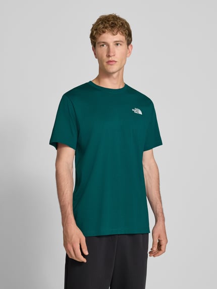 Männermodel trägt t-shirt met labelprint Model 'Evolution' van The North Face in donkergroen katoenmix, regular fit, ruglengte bij maat M 73 cm, frontale borst tot bovenbenen, Ganzkörperansicht von vorne.