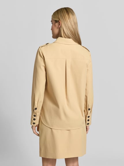 Frauenmodel trägt Longline Langarmbluse mit Schulterklappen von BAUM & PFERDGARTEN in Beige, strukturierte Webware, Zierknöpfe, Rückansicht Ganzkörperansicht.