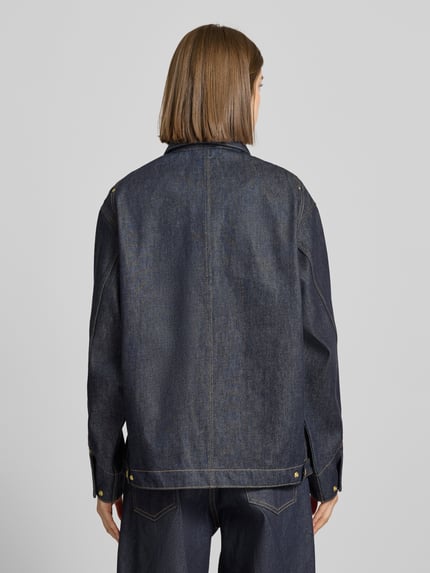 Frauenmodel trägt Regular Fit Jeansjacke mit Logo-Patch Modell 'Arctic' von Carhartt Work In Progress aus dunkelblauer Baumwolle, Rückenansicht.