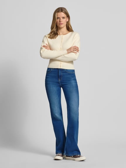Frauenmodel trägt Slim Fit Bootcut Jeans aus baumwoll-mix Modell 'WILLA' von Pepe Jeans, stylizowana na denim, krój slim fit, wysoki stan, naszywka z logo, aplikacja z metką, szlufki na pasek, zapięcie na guzik i zamek błyskawiczny, 5 kieszeni, wykończenie materiału: splot twill, materiał: mieszanka bawełny, kolor niebieski, gładka faktura, ganzkörperansicht von vorne.