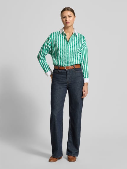 Modelka nosi Regular Fit Hemdbluse mit abgerundetem Saum od Christian Berg Woman, zielono-białe paski, czysta bawełna, krój regular fit, długie rękawy, zapięcie na guziki, kołnierz koszulowy, sportowe mankiety, przód, ujęcie całej sylwetki.