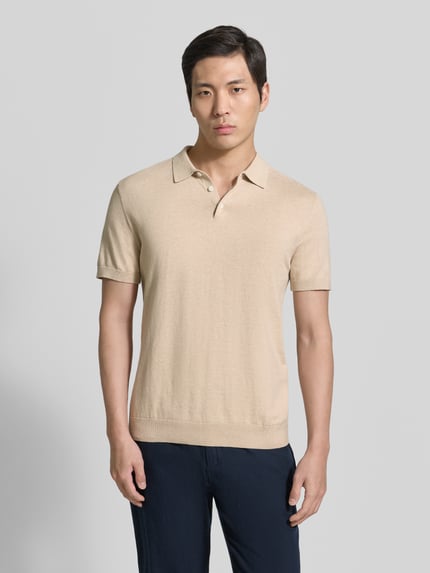Männermodel trägt Regular Fit Poloshirt aus reiner Baumwolle Modell 'BERG' von SELECTED HOMME, unifarben, Feinripp, Ganzkörperansicht von vorne.