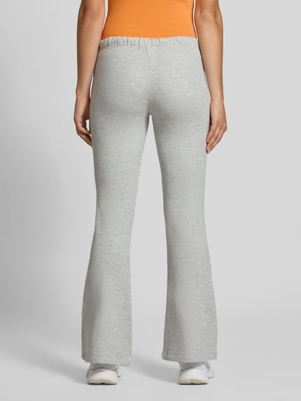 Frauenmodel trägt Flared Sweatpants aus reiner Baumwolle von REVIEW in Hellgrau mit elastischem Bund und seitlichen Eingrifftaschen, Ganzkörperansicht Rückansicht.