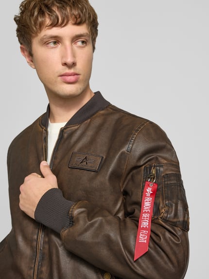 Männermodel trägt Bomberjacke in Leder-Optik mit Label-Details von Alpha Industries, braun, Reißverschluss, Nahaufnahme Oberkörper. Herren Bomberjacke von Alpha Industries, Regular Fit, Kapuze, Stehkragen, Rückenlänge M 63 cm, Schulterbreite M 44 cm, Brustweite M 52 cm, Ärmellänge M 60 cm.
