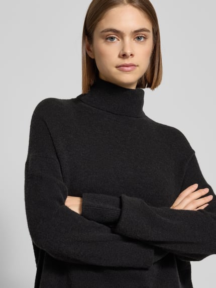 Frauenmodel trägt Regular Fit Rollkragenpullover aus Schurwoll-Mix von Marc O'Polo Denim in schwarzer Melange, Strick, Nahaufnahme Oberkörper.