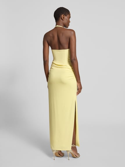 Frauenmodel trägt Neckholder-Maxikleid mit Drapierungen von Forever New in hellgelb, figurbetont, mit Gehschlitz, Ganzkörperansicht Rückansicht.