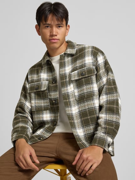 Männermodel trägt Regular Fit Hemdjacke mit Brusttaschen Modell 'REGENT' von JACK & JONES, kariert in Grün und Weiß, Nahaufnahme Oberkörper. Herren Hemdjacke mit Kentkragen, Knopfleiste und strukturierter Oberfläche.