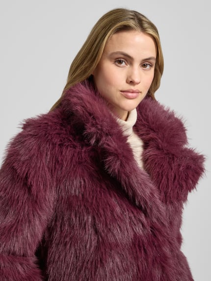 Vrouwenmodel draagt Regular Fit Jacke aus Teddyfell Modell 'NORA' van Vero Moda in effen bordeauxrood, staande kraag, teddytextuur, Nahaufnahme bovenlichaam.