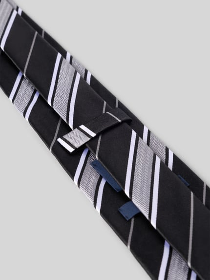 Produktfoto, Krawatte aus reiner Seide von OLYMP in Schwarz mit weißen und grauen Streifen, feine glatte Textur, grauer Hintergrund
