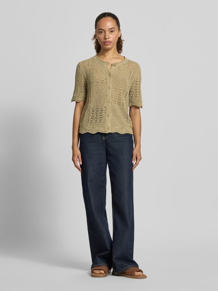 Frauenmodel trägt Regular Fit Strickjacke aus Baumwoll-Mix von Tom Tailor in Beige mit Lochstrickmuster und kurzen Ärmeln, Ganzkörperansicht von vorne.