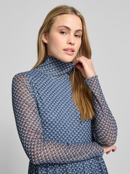 Modelka nosi Midikleid aus Mesh mit Stehkragen od Smith and Soul, mesh, wzór geometryczny, odcień niebieskiego, zbliżenie górnej części ciała.