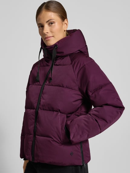 Frauenmodel trägt Regular Fit Steppjacke aus Material-Mix Modell 'Pavinaria' von MSCH Copenhagen in Dunkellila mit Kapuze, Nahaufnahme Oberkörper.