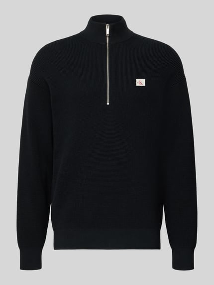 Produktfoto, schwarzer Loose Fit Troyer mit gerippten Abschlüssen und kurzem Reißverschluss von Calvin Klein Jeans, Label-Detail auf Brust.