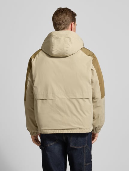 Männermodel trägt Jacke mit Kapuze Modell 'Lao' van WOODBIRD in beige katoenmix, regular fit, rugaanzicht, context: herenjack, verborgen rits, steekzakken, ruglengte 71 cm, schouderbreedte 55 cm, borstwijdte 69 cm, mouwlengte 66 cm. Ganzkörperansicht Rückansicht.