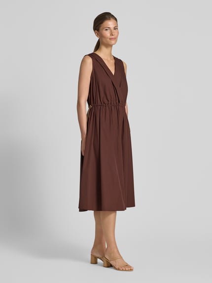 Frauenmodel trägt Knielanges Cocktailkleid mit Kordelzug und Kordelstoppern von Rinascimento in Braun aus Baumwolle, taillierter Schnitt, V-Ausschnitt, knieumspielend, schlichte Optik, Ganzkörperansicht von vorne.