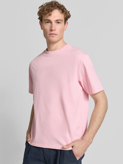 Männermodel trägt Oversized T-Shirt mit Rundhalsausschnitt von Lindbergh in Rosa aus Reine Baumwolle, Rückenlänge 69 cm bei Größe M, Ganzkörperansicht von vorne.