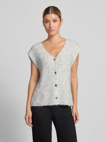 Kobiece modelka nosi kamizelkę dzianinową Strickweste mit V-Ausschnitt Modell 'Xandra' od Neo Noir, Mieszanka materiałów z mieszanką bawełny, krój regular fit, Listwa guzikowa, Długość tyłu w rozmiarze 36: 58 cm, jasnoszary melanż, wyraźna struktura dzianiny, widoczne metalowe guziki, Ganzkörperansicht von vorne