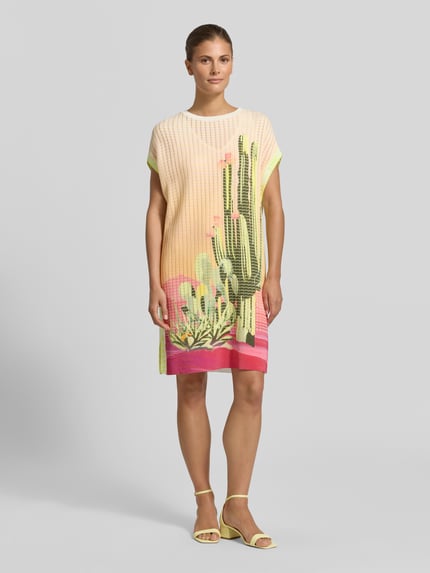 Kobiece modelka nosi Knielanges Kleid mit Strukturmuster und Rundhalsausschnitt von Marc Cain, mieszanka bawełny, krój straight fit, długość do kolan, fakturowany wzór, okrągły dekolt, krótkie rękawy, długość tyłu w rozmiarze 36: 89 cm, szerokość w rozmiarze 36: 57 cm, długość rękawów w rozmiarze 36: 22 cm, kolor żółty, różowy i zielony z motywem kaktusa, całkowity widok z przodu.