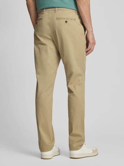 Männermodel trägt Slim Fit Chino mit Eingrifftaschen von GAP, beigefarbener Baumwoll-Elasthan-Mix, Ganzkörperansicht Rückansicht.