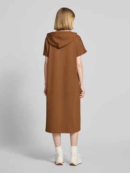 Frauenmodel trägt Sweatkleid mit Kapuze von Soyaconcept in Braun, Material-Mix mit Modal-Anteil, Gerader-Schnitt, Midikleid, Label-Print, Ganzkörperansicht Rückansicht.