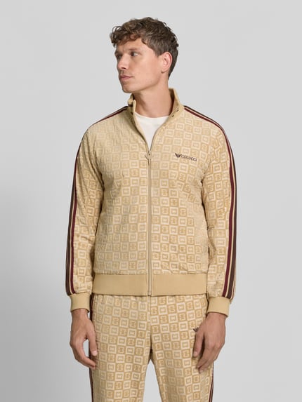 Męski model nosi Regular Fit Sweatjacke mit Label-Stitching von COLUCCI, mieszanka bawełny, stójka, zamek błyskawiczny, wzór w kratę, długość tyłu 62 cm, długość rękawów 65 cm, beżowe i brązowe odcienie, wyraźna tekstura, całkowity widok z przodu.