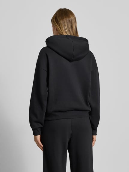 Kobiece model prezentuje bluzę z kapturem z logo i kieszenią kangurka od JJXX z mieszanki bawełny, krój relaxed fit, widok z tyłu.