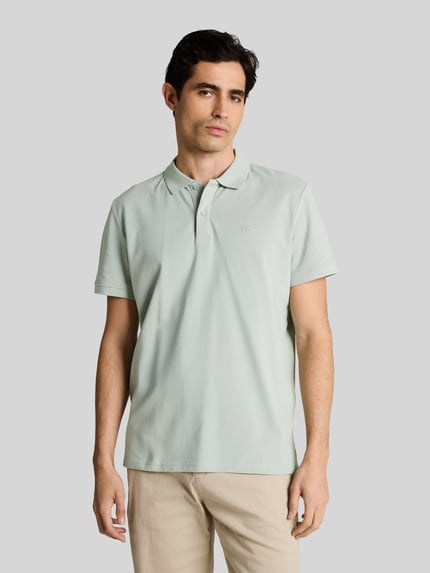 Männermodel trägt Regular Fit Poloshirt aus reiner Baumwolle von Tom Tailor in Optik: Unifarben mit Logo-Stitching, Piqué-Struktur, Nahaufnahme Oberkörper.