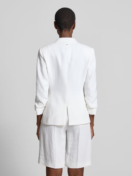 Frauenmodel trägt Slim Fit Kurzblazer aus Leinen-Viskose-Mix Modell 'JIA8' von BOSS in weißer Melange-Optik, Twill-Materialverarbeitung, Ganzkörperansicht Rückansicht.