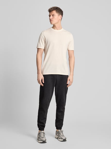 Männermodel trägt Sweatpants mit Logo und elastischem Bund von GAP aus Baumwoll-Mix in Schwarz, Regular-Fit, Ganzkörperansicht von vorne.